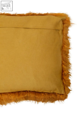 A mustard-yellow bosie real mongolian lamb fur cushion with plush fuzzy fringe trim