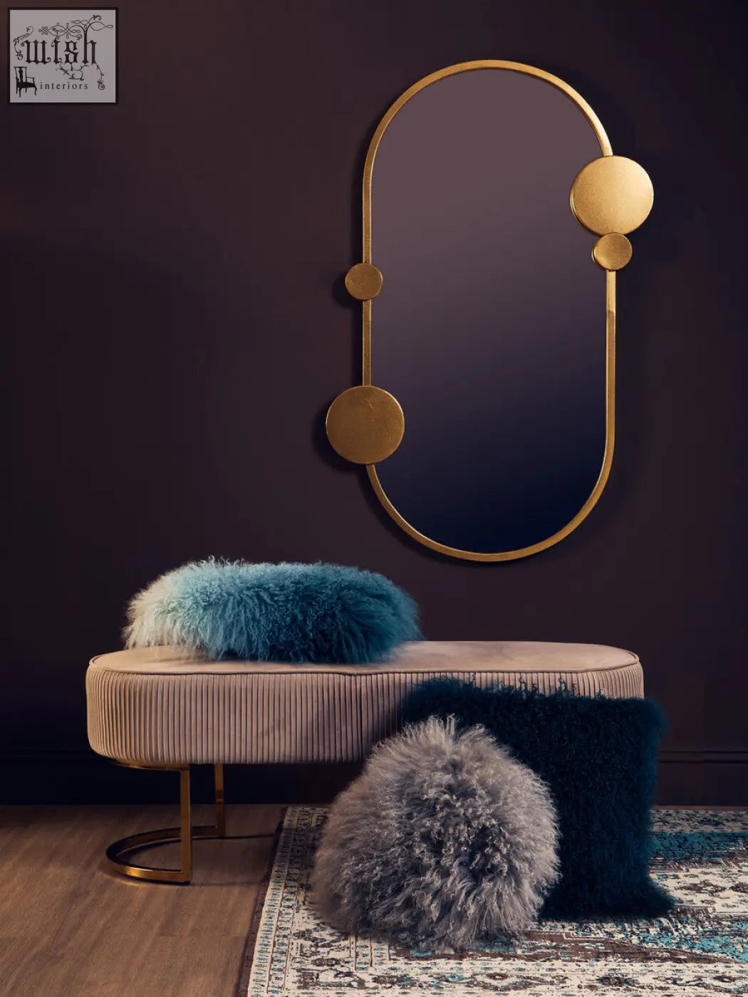 Gold-toned oval mirror with circular accents mounted above a bosie real mongolian fur teal square cushion