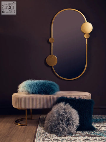 Gold-toned oval mirror with circular accents mounted above a bosie real mongolian fur teal square cushion