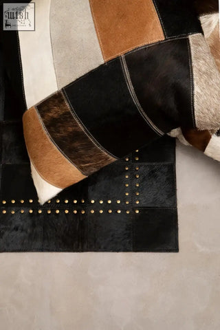 Black and tan cowhide patchwork leather patchwork cushion with gold-tone nailhead trim from bosie safira collection