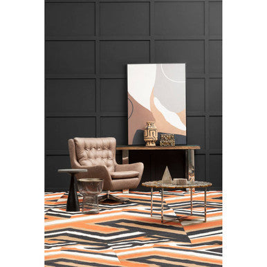 Beige tufted armchair with soft leather upholstery next to a bosie villon zig zag pattern rug with bold zig zag design