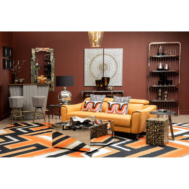 Vibrant yellow leather sofa with bold orange and black throw pillows featuring a villon zig zag pattern rug nearby