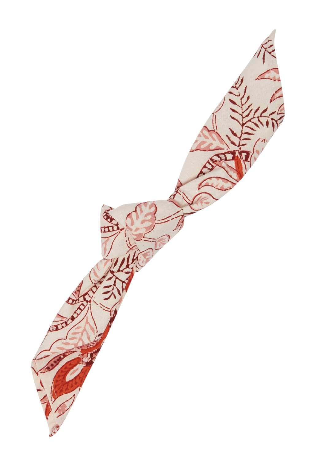 A cream fabric headband with a tied knot and rust botanical print complementing bossa nova table napkin set