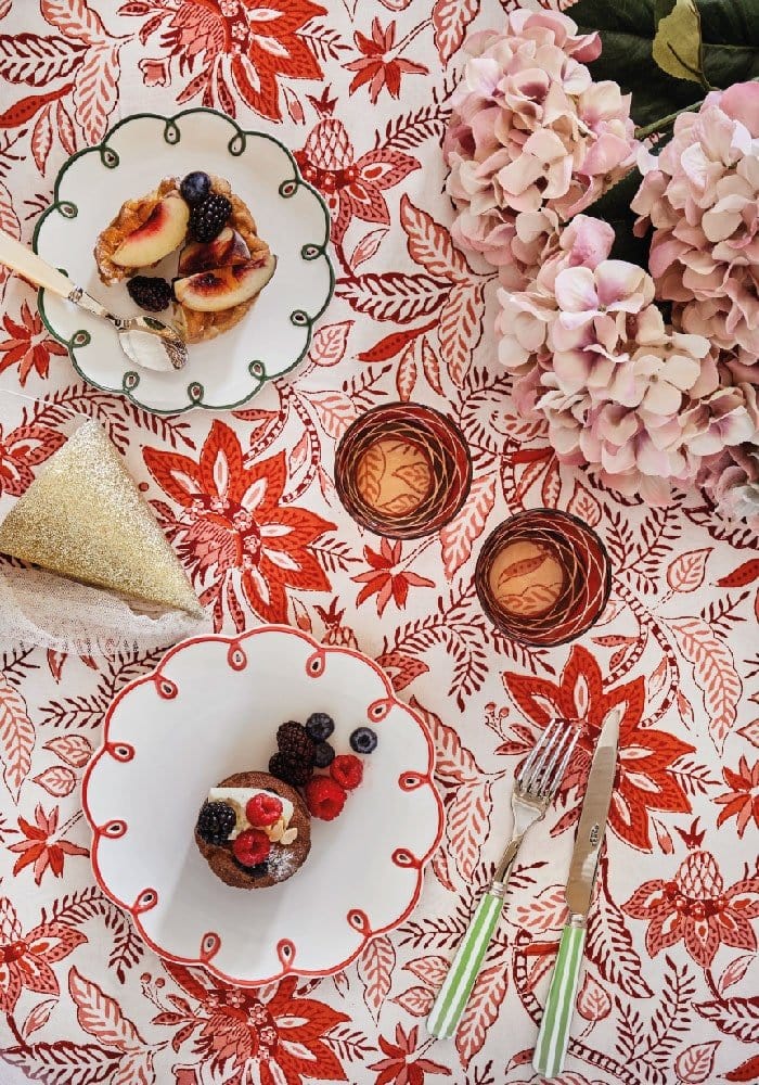 A white ceramic plate with a red decorative border and desserts on a bossa nova red tablecloth