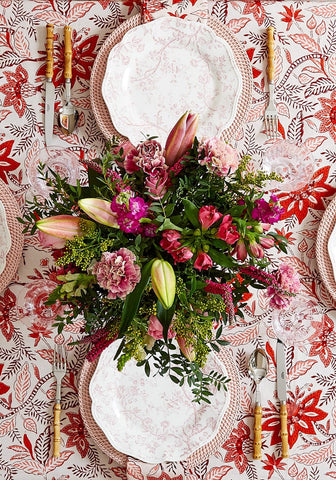 A vibrant floral centerpiece with pink purple and green blooms on a red bossa nova tablecloth for lively decor