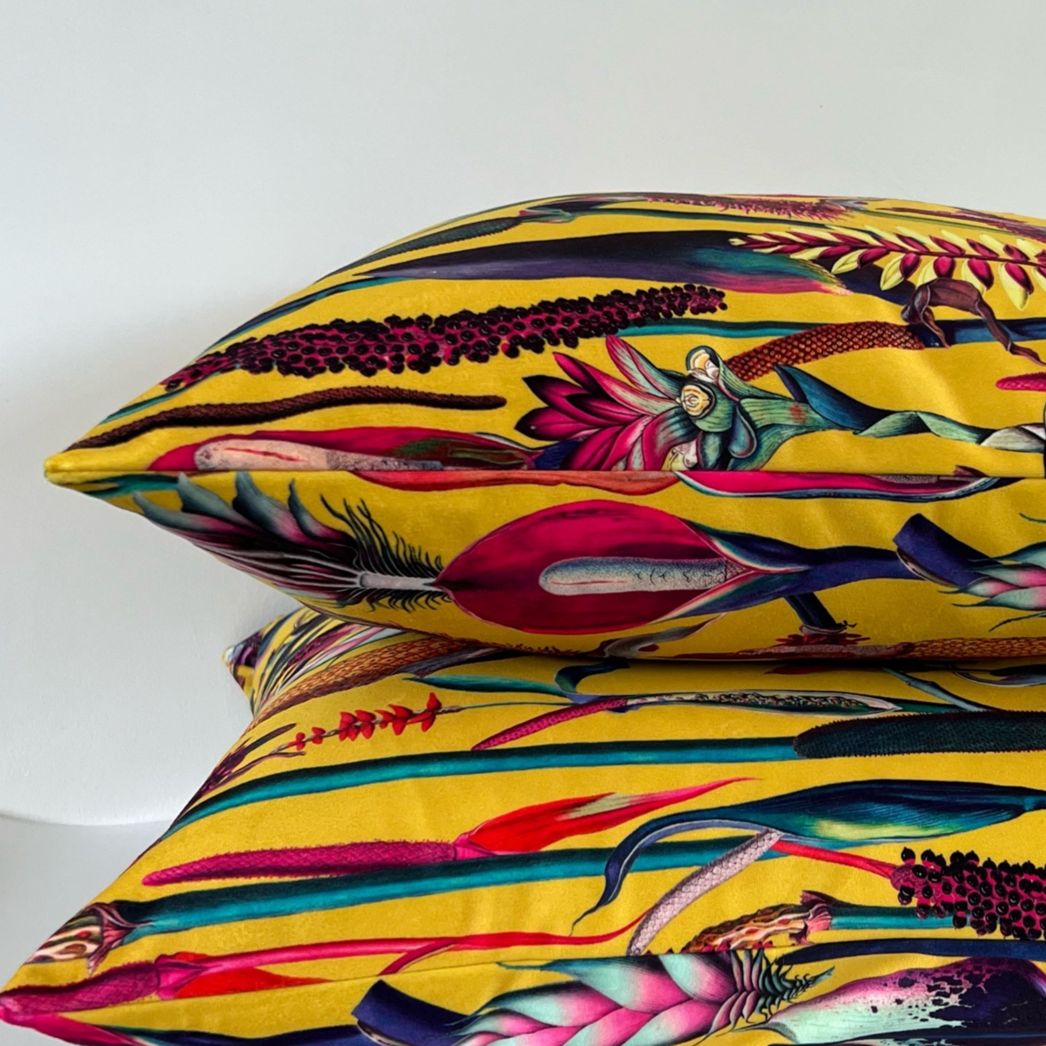 Vibrant botanical mustard velvet throw cushion with bold tropical floral print in pink red teal and black