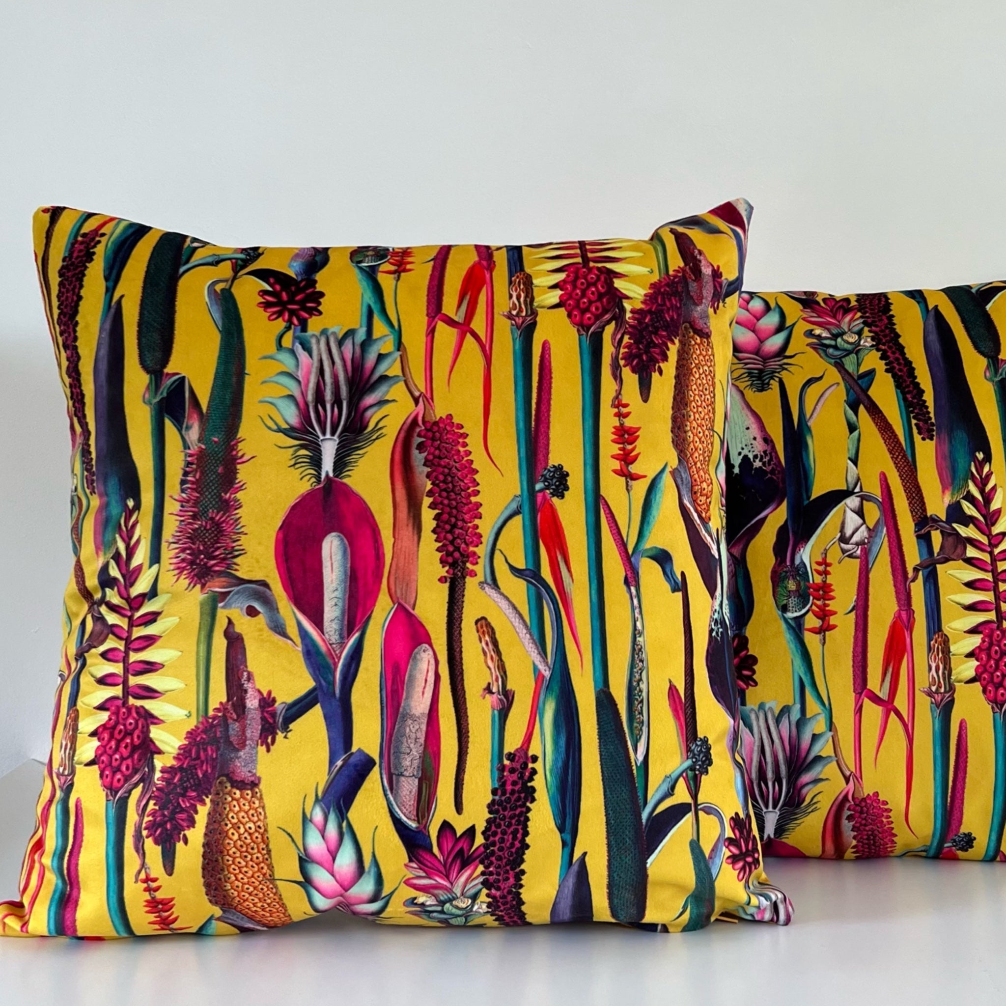 Vibrant botanical mustard velvet throw cushion with bold tropical print in reds pinks and deep greens on plush fabric