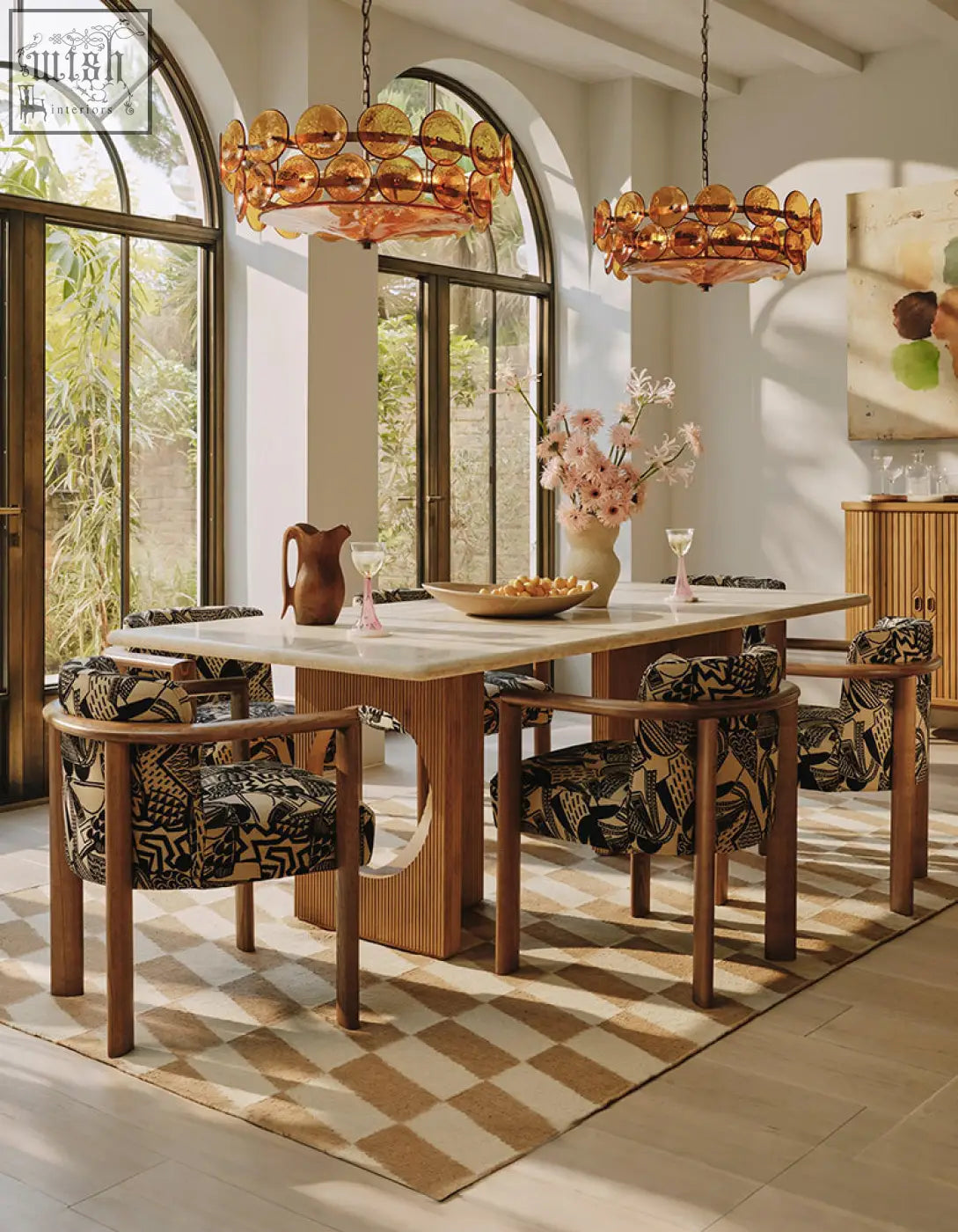 Amber glass chandelier with circular layered discs hangs above boucheron dining table in travertine and solid wood dining area