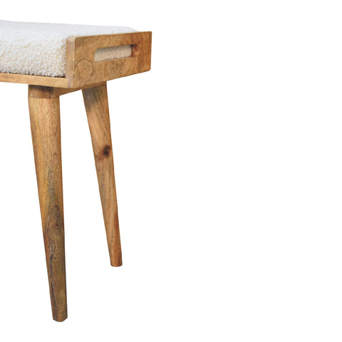 A rustic wooden tray style footstool with tapered legs and a white boucle cream textured cushioned seat