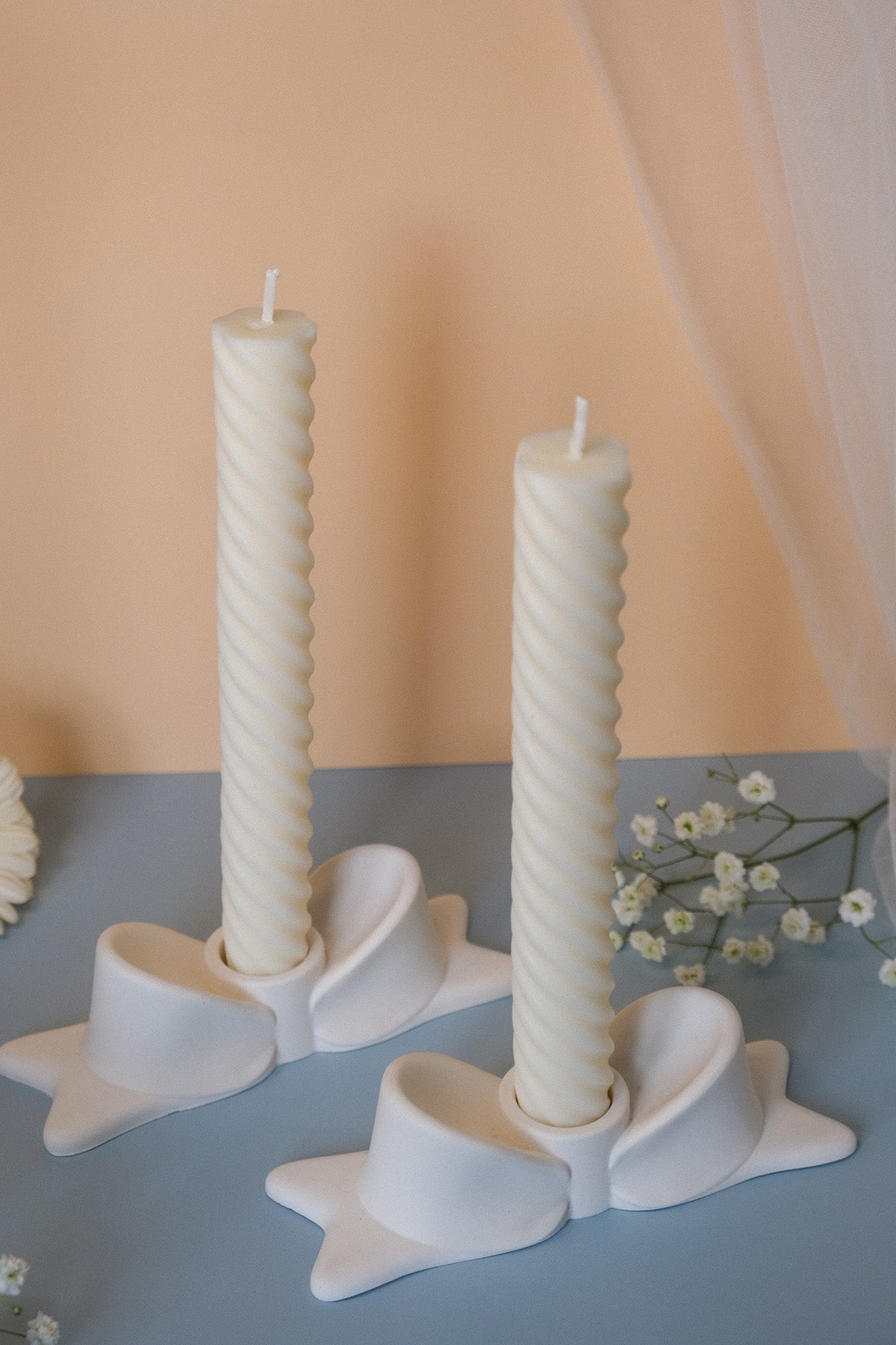 Two off-white twisted ceramic bow candle holders perfect as elegant bow candle decor for any room