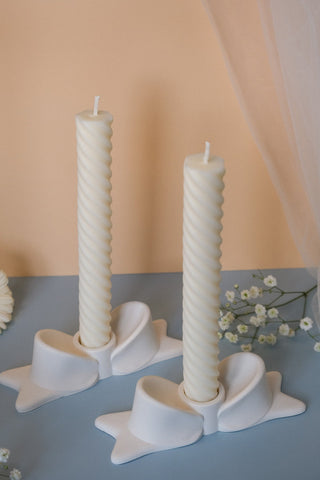 Two off-white twisted ceramic bow candle holders perfect as elegant bow candle decor for any room