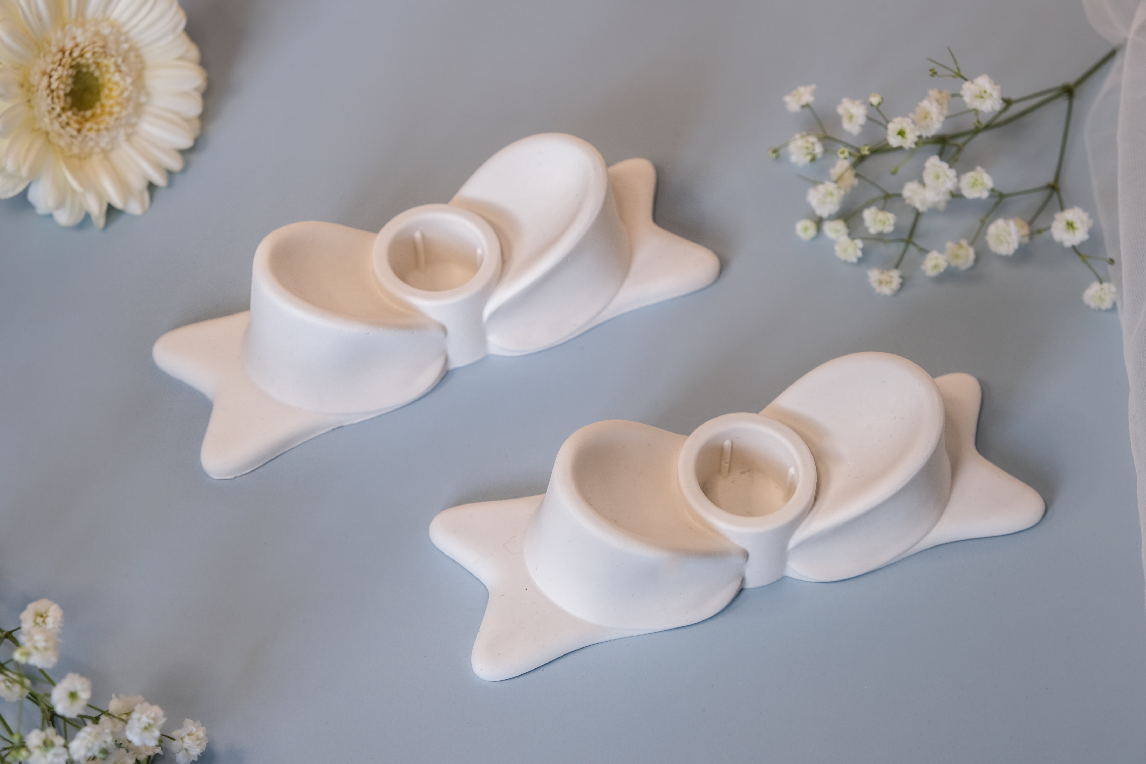 White ceramic bow candle holder with central circular opening made from jesmonite item for decorative lighting