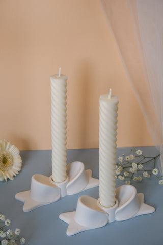 White twisted pillar candles in matching star-shaped ceramic bow candle holders for elegant decor