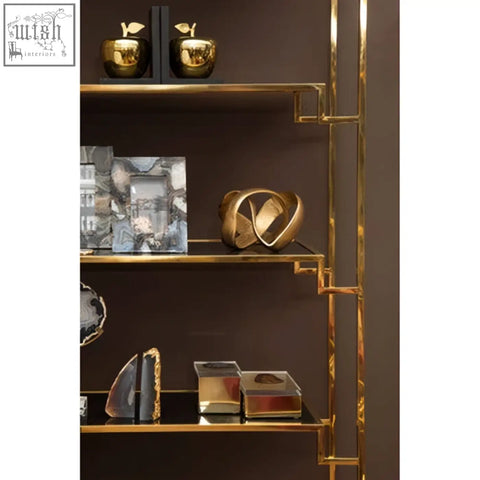 Gold-toned geometric sculpture with polished surfaces on modern shelving next to the bowerbird black agate trinket box