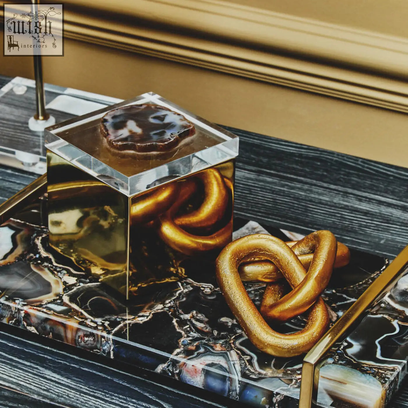 Gold-finished knot sculpture with glossy metallic finish on dark marble tray for bowerbird black agate trinket box