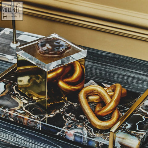 Gold-finished knot sculpture with glossy metallic finish on dark marble tray for bowerbird black agate trinket box