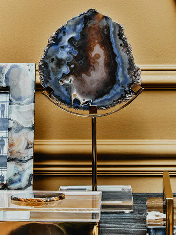 A stunning blue and brown bowerbird black and gold agate sculpture on a sleek stand showcasing gold agate details