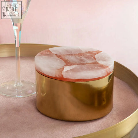 A round quartz trinket box with a gold finish and a translucent pink and white marble lid by bowerbird