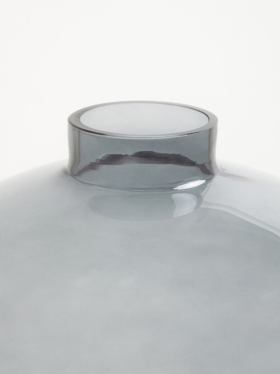 A sleek bree grey glass vase with a smooth rounded body and wider rim made of translucent grey glass