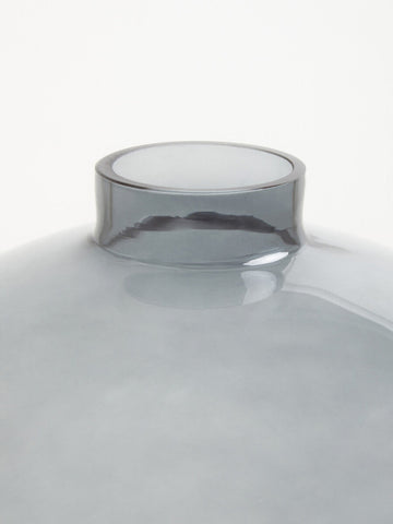 A sleek bree grey glass vase with a smooth rounded body and wider rim made of translucent grey glass