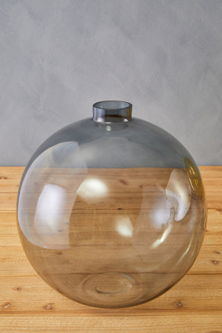 A bree grey glass vase made of sleek translucent grey glass with a rounded body and narrow metallic rim