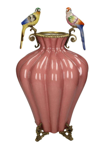 A pink ceramic bridgerton regency style vase with gold metal accents and two colorful parrot figurines on handles