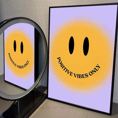 A framed bright positivity print featuring a bold yellow smiley face and positive vibes only text on lavender background