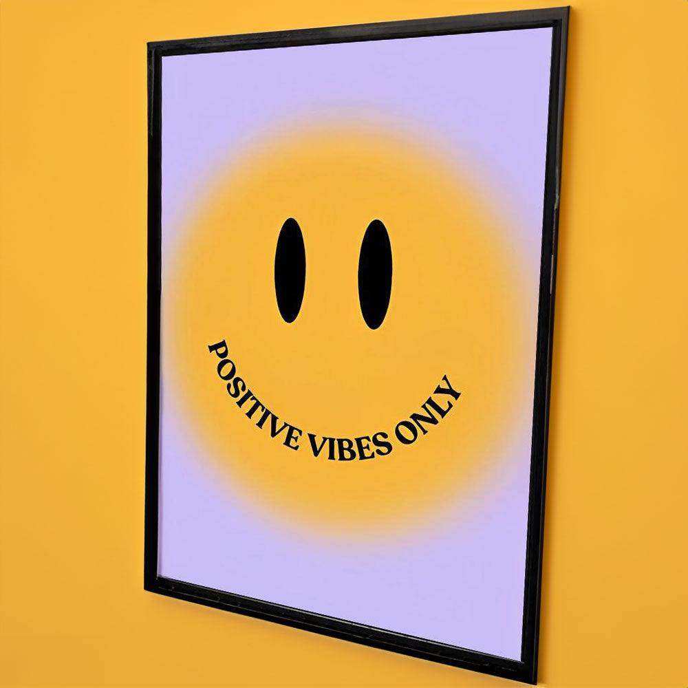 A framed bright positivity print with a smiling face and positive vibes only on a yellow to lavender gradient background