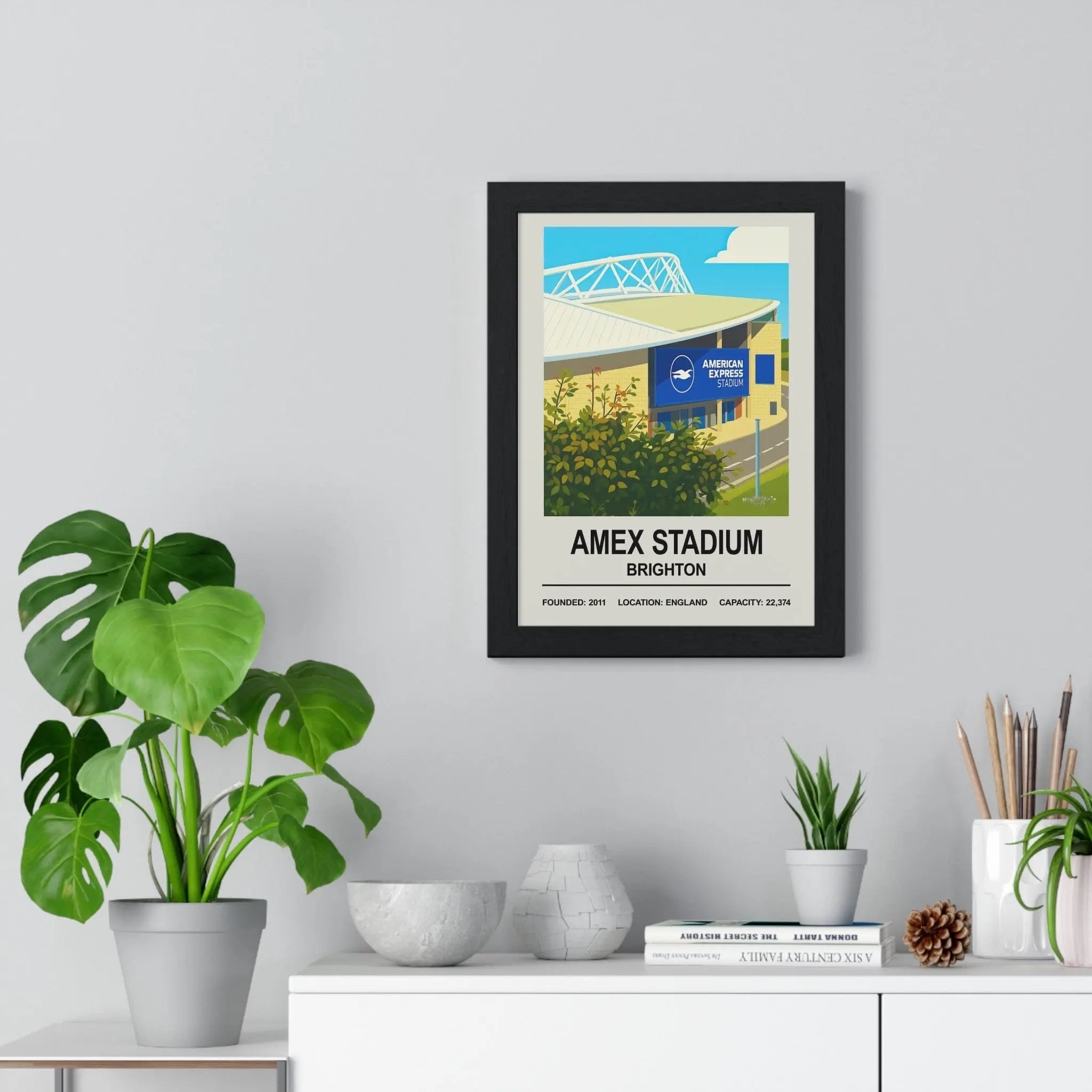 Black-framed poster print of amex stadium in brighton featuring a bright stylized illustration of the architecture and branding