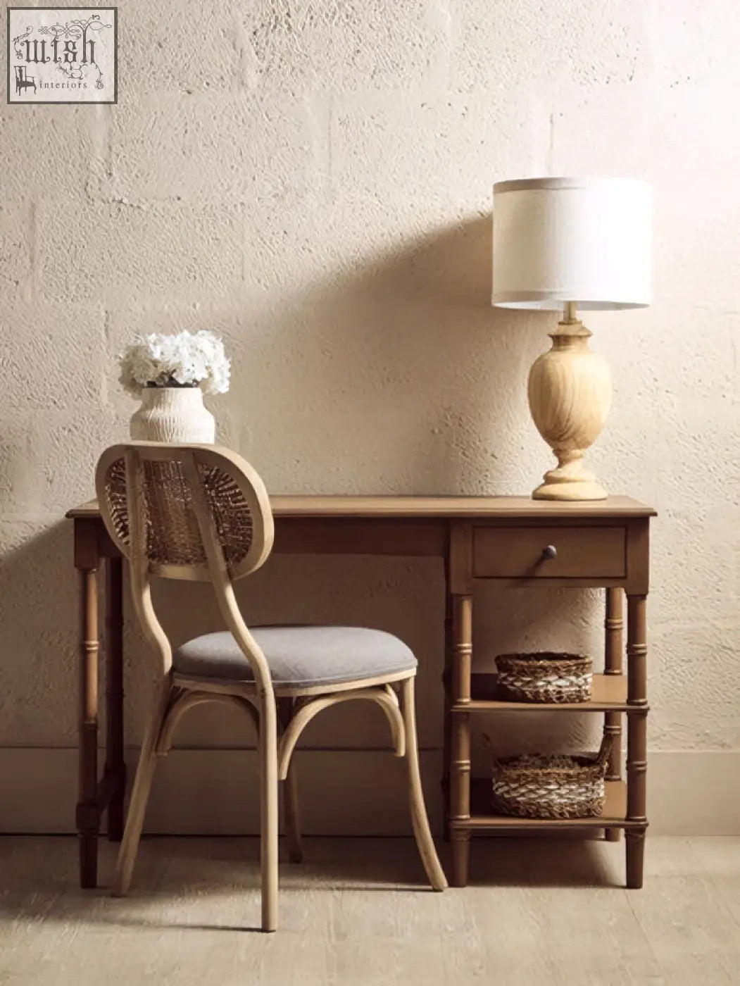 Brown pine wood console table with one storage drawer two shelves topped by beige lamp and white vase with flowers
