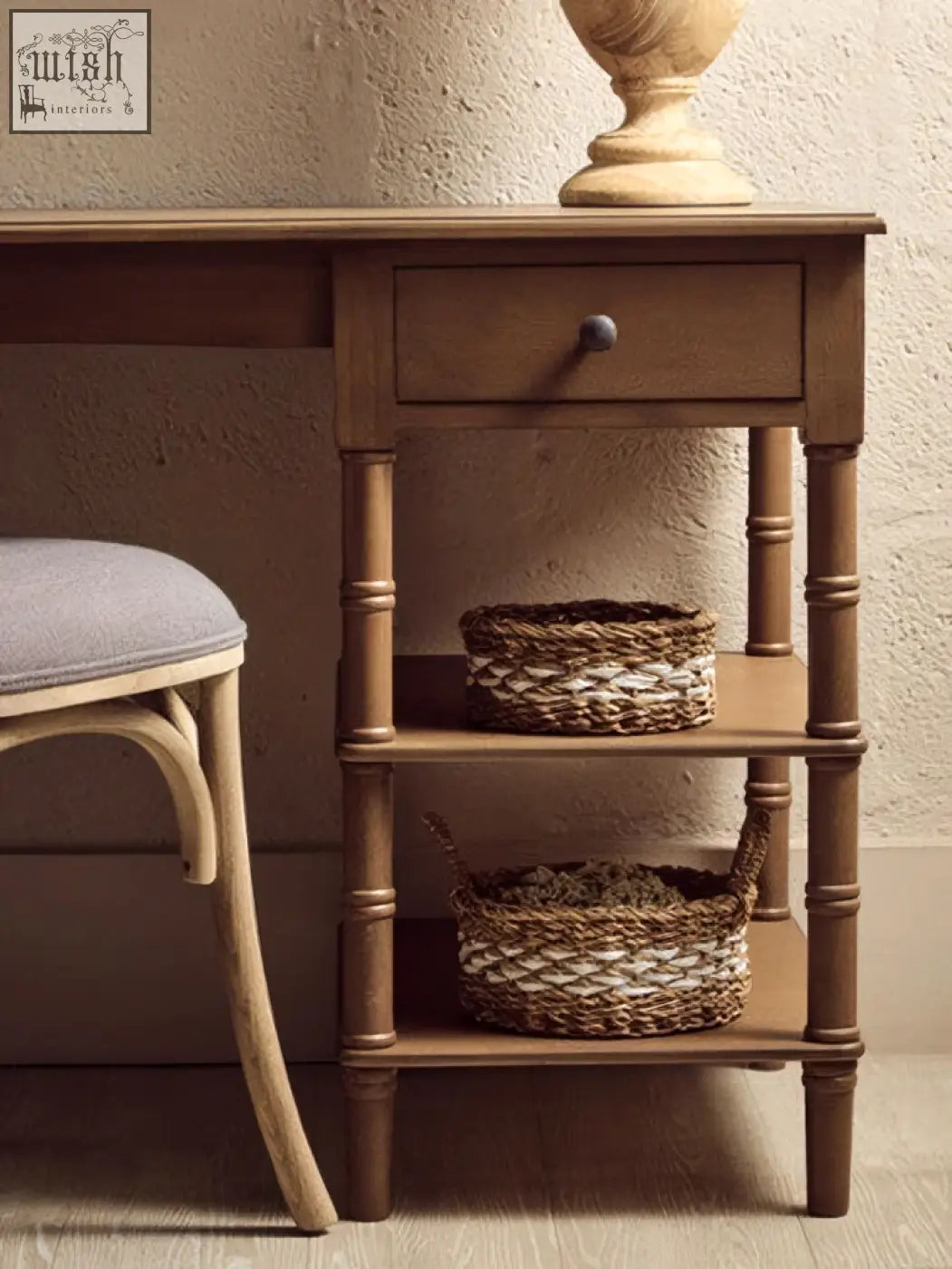 Brown pine wood console table with single drawer and shelves holding woven baskets made of natural fibers