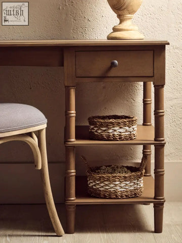 Brown pine wood console table with single drawer and shelves holding woven baskets made of natural fibers
