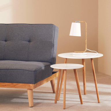 Gray tufted sofa with wooden legs next to a bruin white metal table lamp for cozy living room lighting