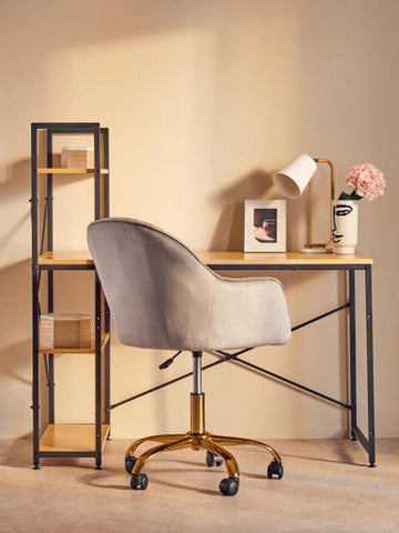 Gray velvet office chair with gold-tone base beside bruin table lamp with white metal and glass shade