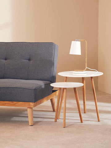 Modern minimalist bruin table lamp with white metal base on a white marble top table with slender wooden legs