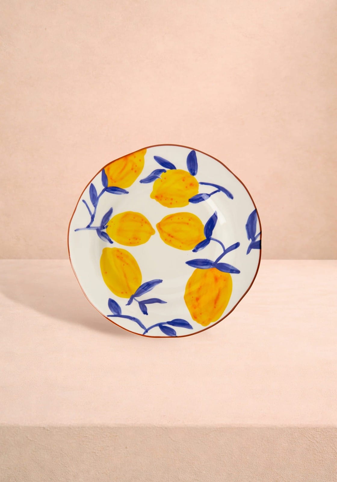 A white ceramic lunch plate hand painted with yellow lemons and blue leaves from buds in may set inspired by matisse