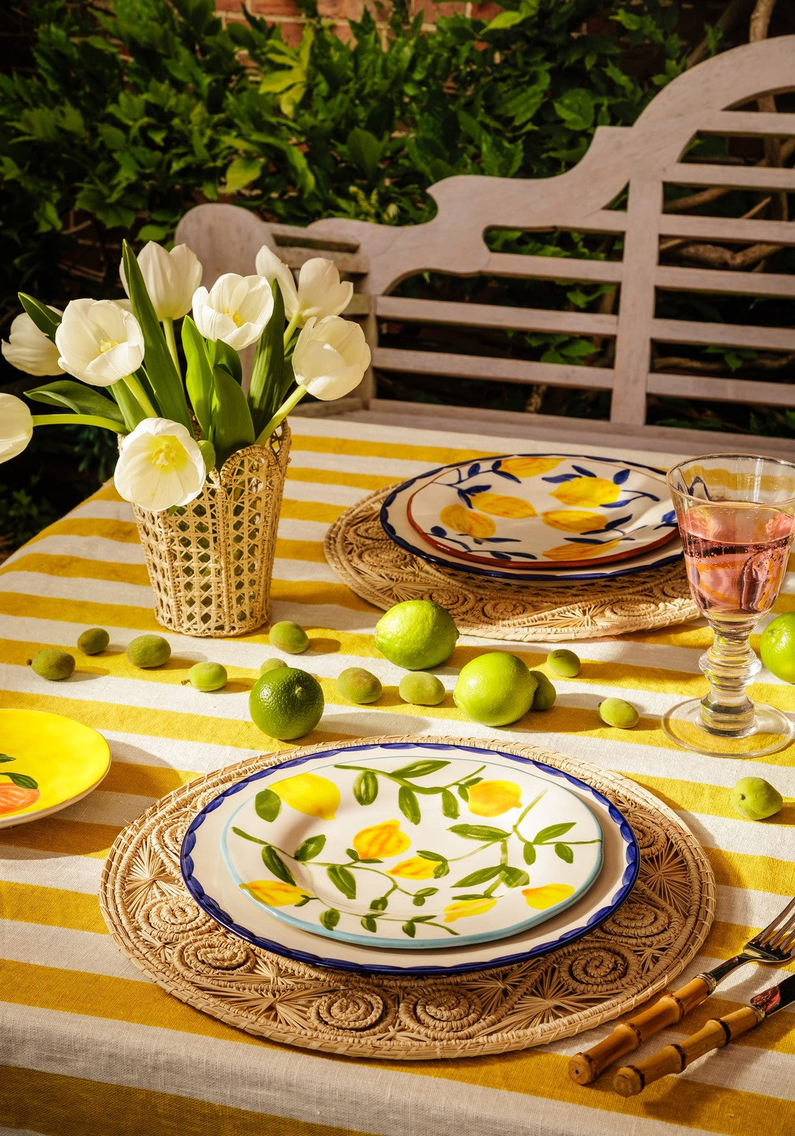 Yellow and white striped ceramic lunch plate with hand-painted lemon design blue rim on woven placemat