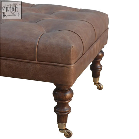 Brown buffalo leather storage bench in rectangular form with tufted top dark wood legs and brass casters for extra seating