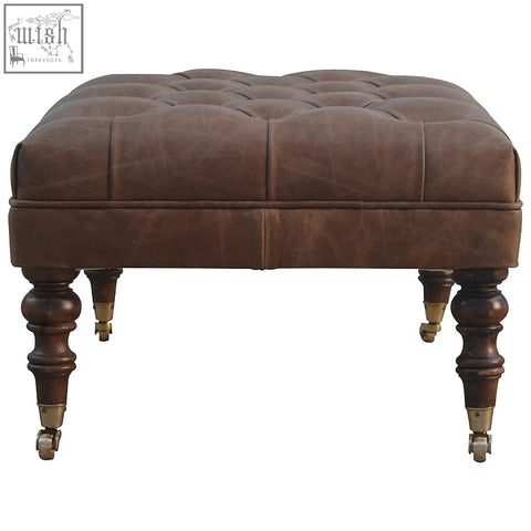 Brown buffalo leather tufted rectangular ottoman with dark wood legs and brass casters for additional seating