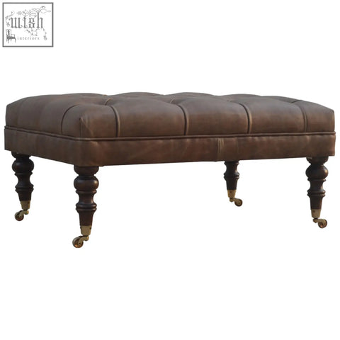 Brown buffalo leather storage bench with rectangular form tufted top dark wooden legs and brass casters for additional seating