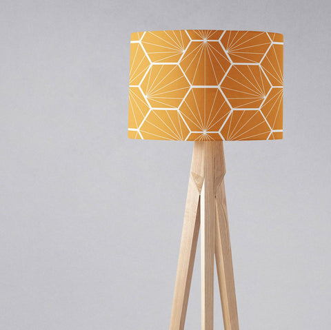 Butterscotch yellow table lamp shade with white geometric hexagons on a light wood tripod base