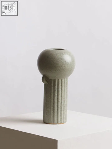 A sleek matte sage green ceramic calcita large speckled green vase with a rounded bulbous top and ribbed stem