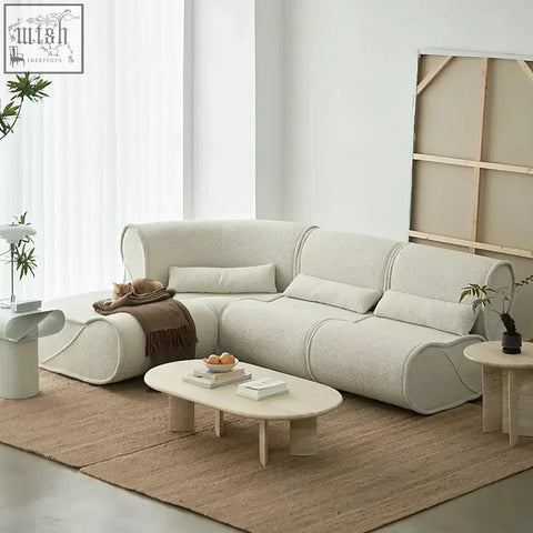Cream-colored plush modular three seater corner sofa with soft rounded edges and matching cushions calderón model