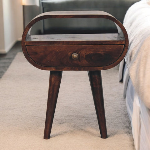 Dark brown california walnut circular bedside table with curved top tapered legs and open slot for storage