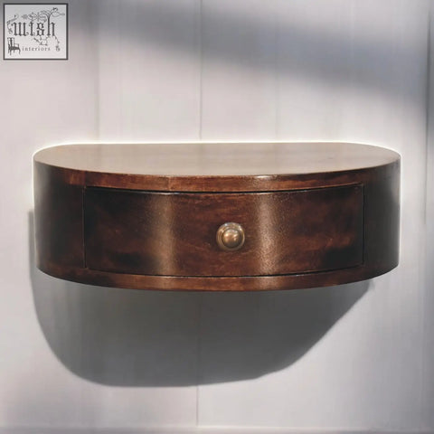 A sleek california walnut wall mounted rounded bedside table with dark brown finish and polished brass knob