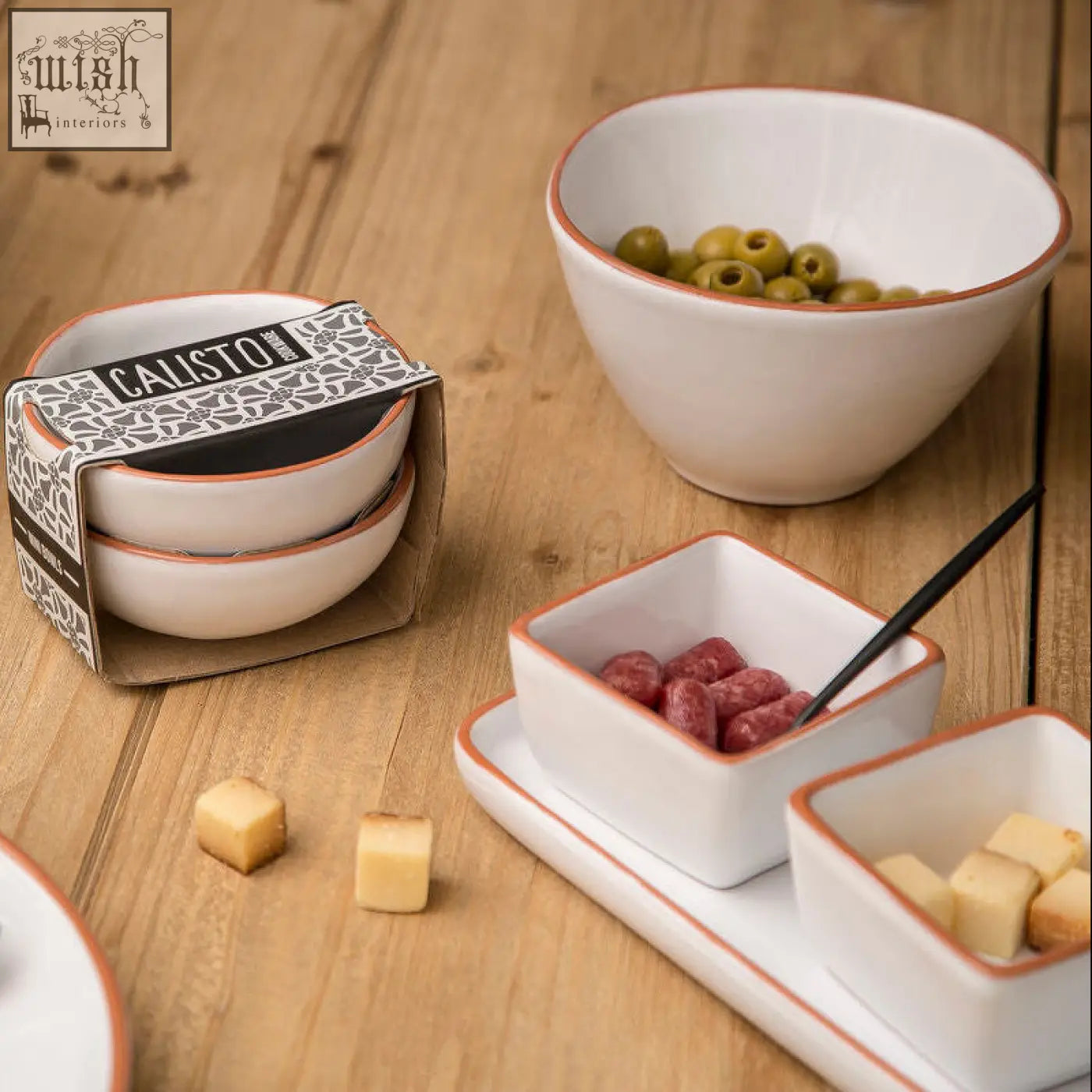 White glazed cereal bowls with terracotta rims displayed stacked and holding olives cheese and cured meats on a tray