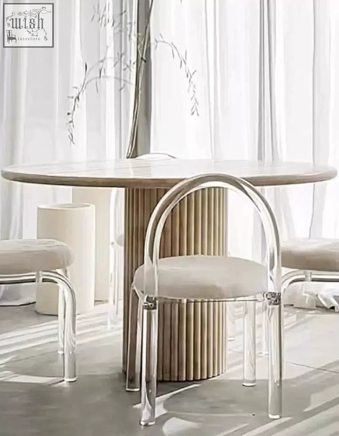 A modern chair with clear acrylic frame and beige seat paired with a callista round dining table marble