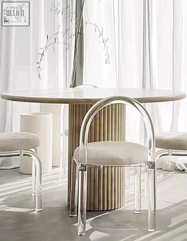 A modern chair with clear acrylic frame and beige seat paired with a callista round dining table marble