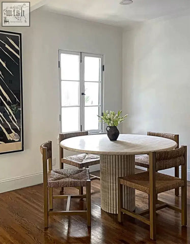 Round dining table callista with marble top and light wooden fluted base paired with woven wicker chairs