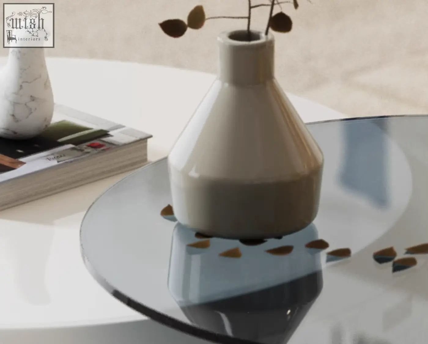 A sleek off-white ceramic vase with dried leaves on the calloway nesting coffee table set with 3 tables
